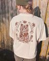 Person wearing a beige t-shirt with a bear design against a wooden background